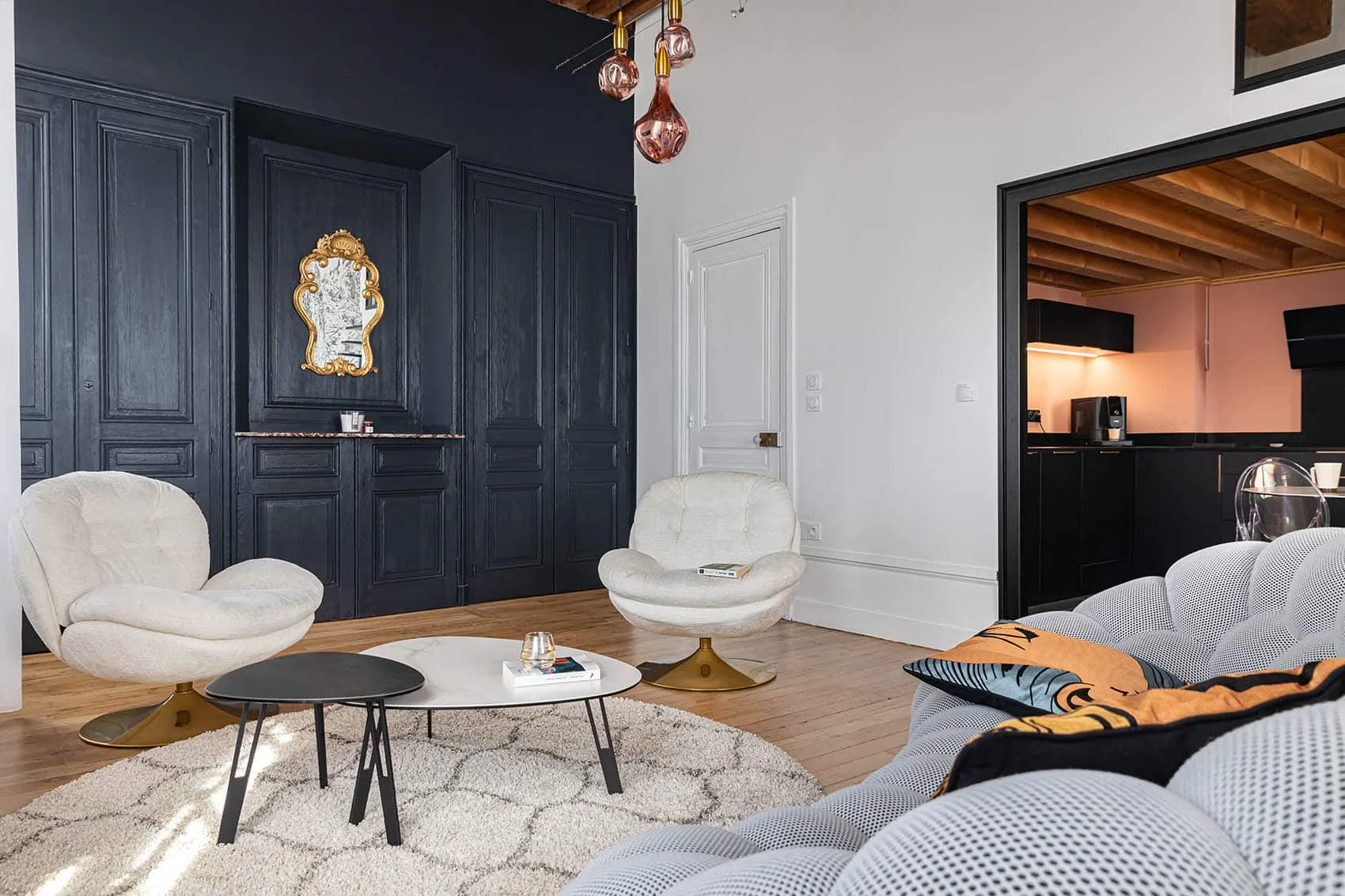 Salon de l’appartement canut Austerlitz à Lyon : murs gris anthracite, miroir doré et fauteuils blancs, décoration contemporaine