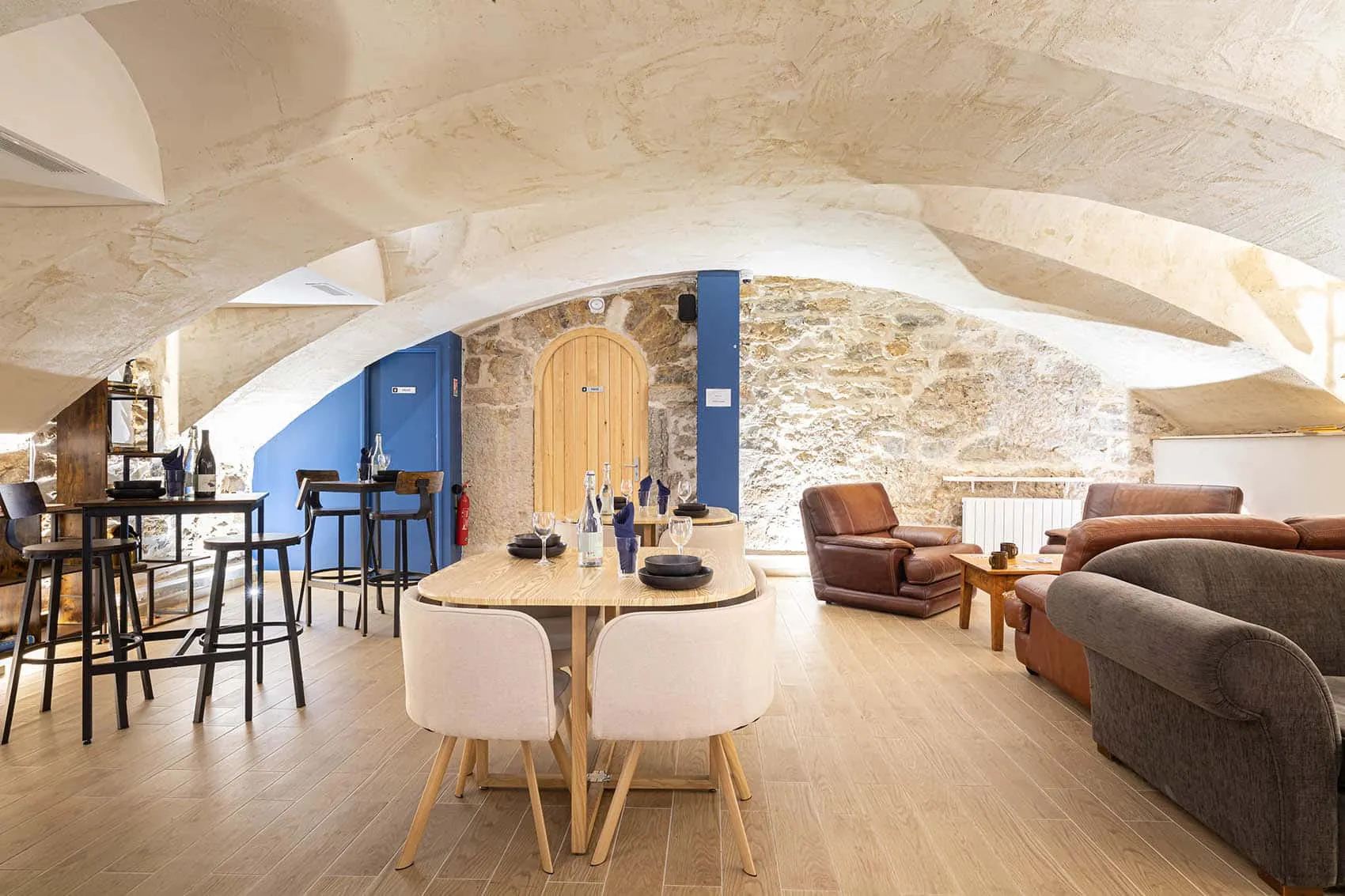 Salle voûtée du restaurant Le Dérobé à la Croix-Rousse : pierres apparentes, tables hautes et mobilier en bois