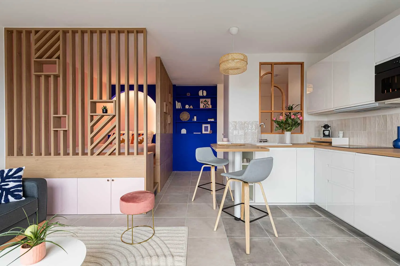 Studio neuf en VEFA personnalisé à Lyon : claustra en bois, niche bleu Klein et cuisine blanche avec bar