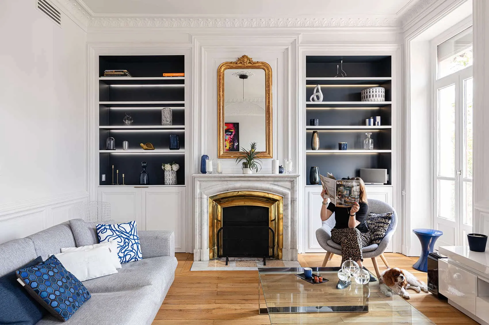 Salon de l’appartement bourgeois de la Croix-Rousse rénové par une architecte d’intérieur à Lyon : cheminée en marbre, miroir doré, bibliothèques bleu nuit