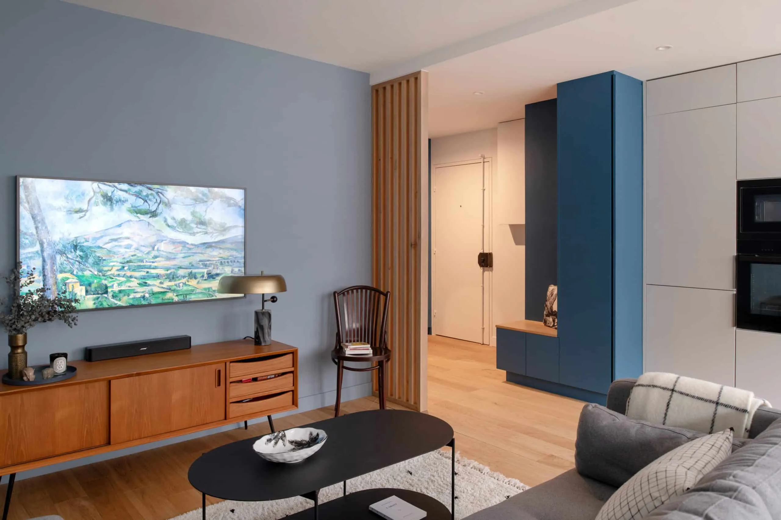 Salon de l’appartement Bugeaud rénové à Lyon : mur bleu, enfilade vintage et tasseaux de bois, décoration scandinave