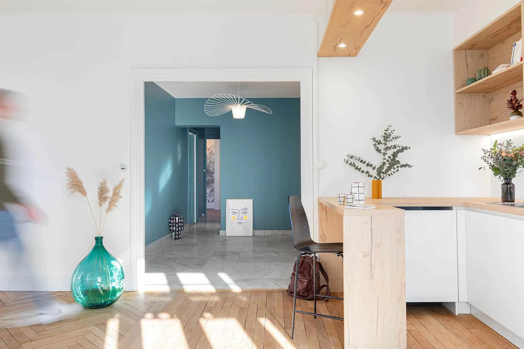 Appartement Garibaldi rénové à Lyon : entrée bleu clair et cuisine ouverte sur la pièce de vie